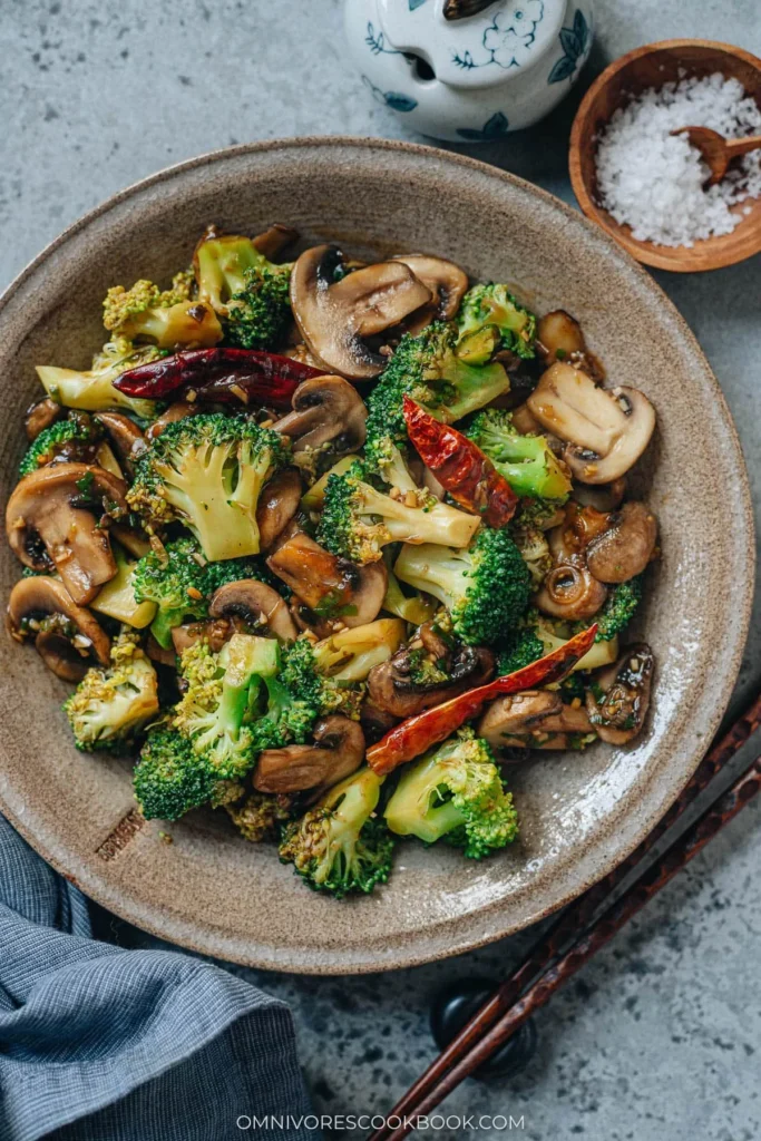 Colorful broccoli mushroom stir fry served in a bowl with a sprinkle of sesame seeds.